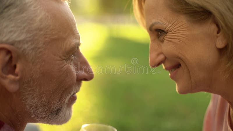 Smiling elderly couple looking at each other with love and tenderness, park date royalty free stock photography Smiling elderly couple looking at each other with love and tenderness, park date royalty free stock photography