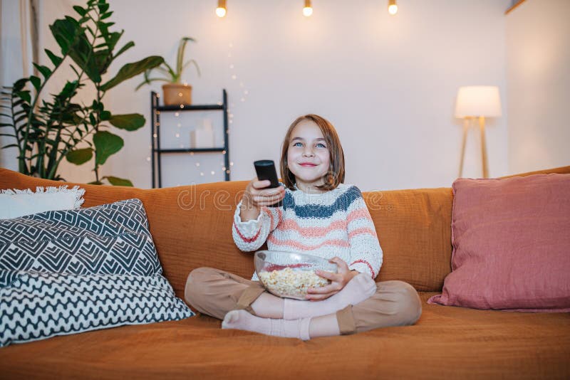 Entertained Smiling Children Sitting On A Couch Watching  Tv  Eating Popcorn Stock Photo Image 