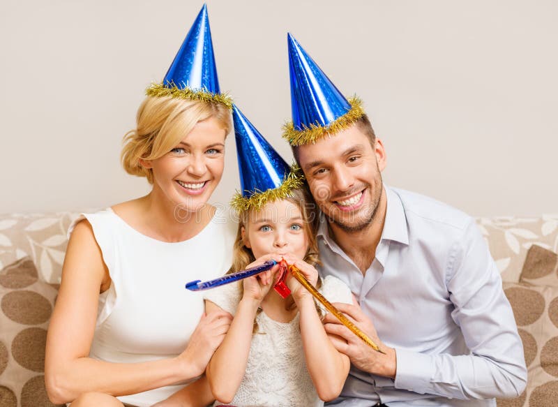 Smiling family in blue hats blowing favor horns