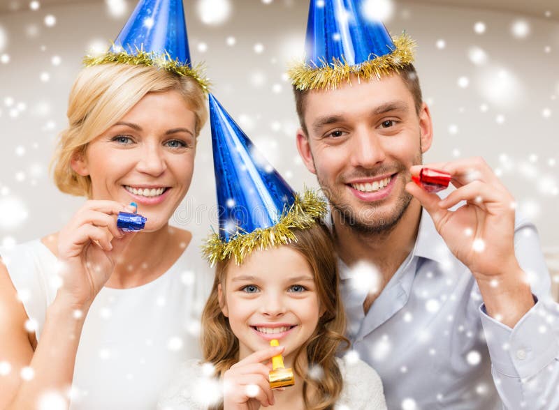 Smiling family in blue hats blowing favor horns