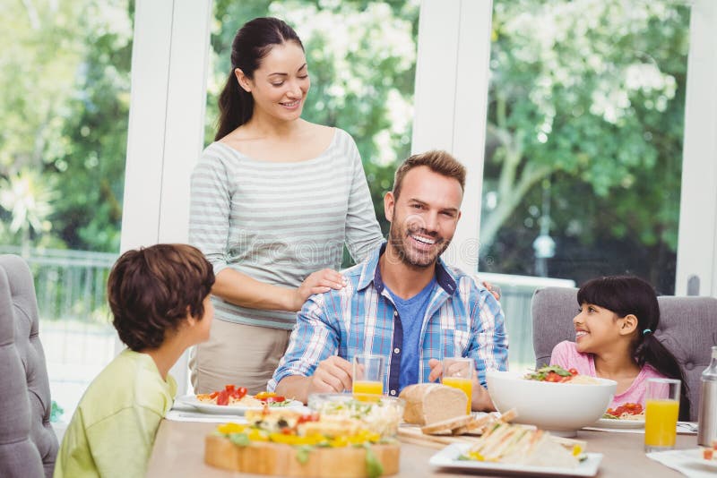 Smiling Family with Mother Standing at Dining Table Stock Image - Image ...