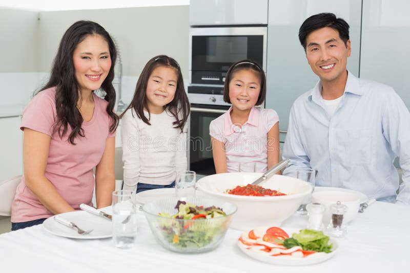 Smiling Family Sitting at Dining Table in Kitchen Stock Photo - Image ...