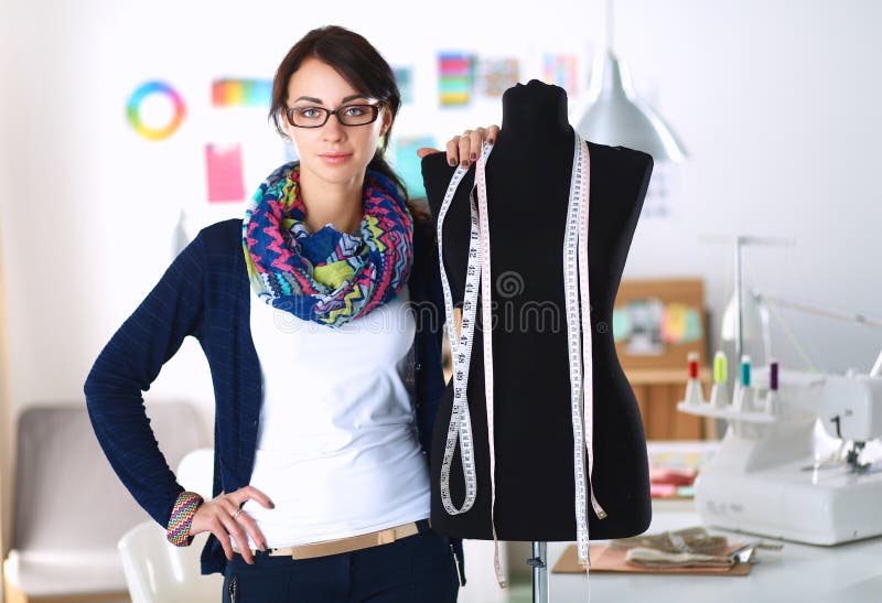 Smiling fashion designer standing near mannequin in office