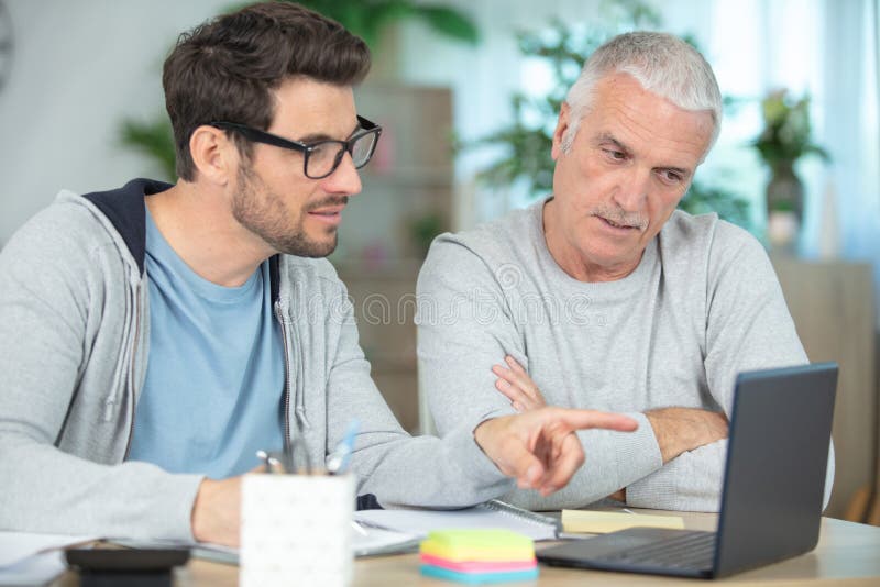 smiling father and son with laptop while sitting at desk