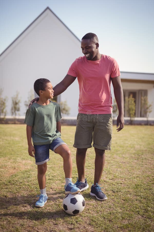 Smiling father and son standing in garden with football royalty free stock image Smiling father and son standing in garden with football royalty free stock image