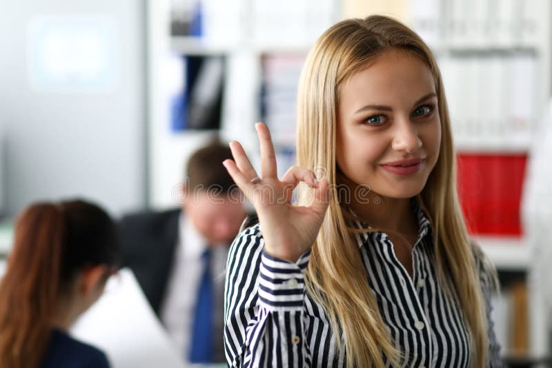 Smiling female clerk showing OK or confirm sign with her arm royalty free stock photo Smiling female clerk showing OK or confirm sign with her arm royalty free stock photo