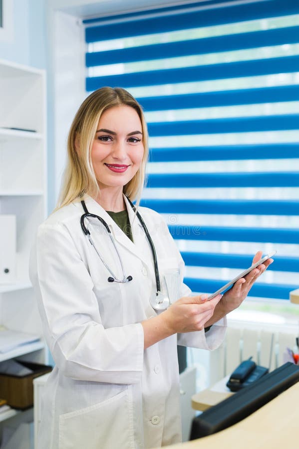 Smiling female doctor with tablet at the reception looking at the camera. royalty free stock photography Smiling female doctor with tablet at the reception looking at the camera. royalty free stock photography