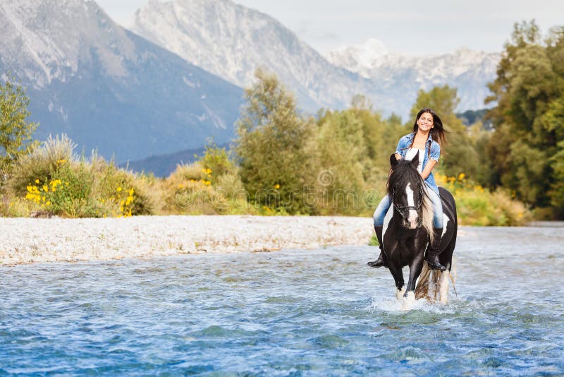 Smiling Female horse rider crossing river