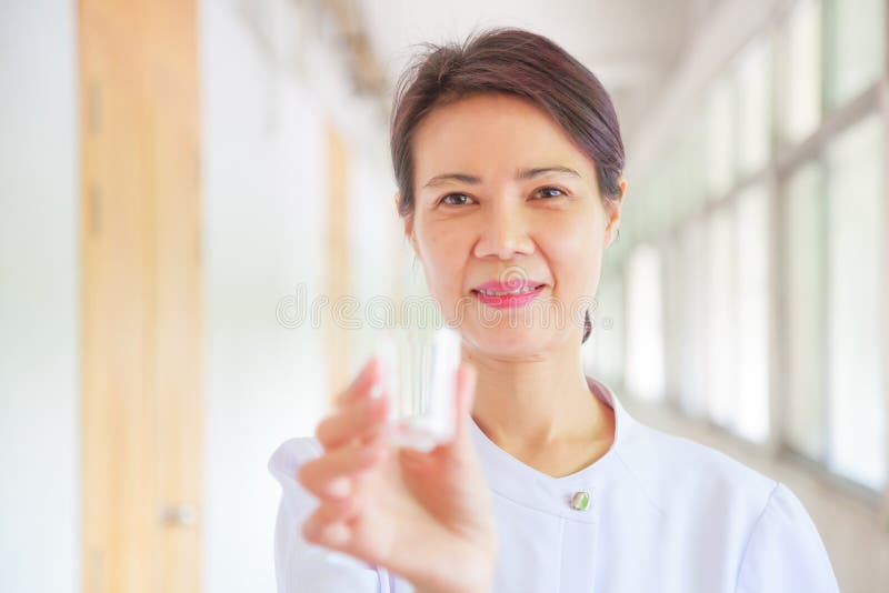 Smiling female nurse holding pill cup in her hands for patients. Professional, Specialist, Nurse, Doctor in white uniform concept royalty free stock images Smiling female nurse holding pill cup in her hands for patients. Professional, Specialist, Nurse, Doctor in white uniform concept royalty free stock images