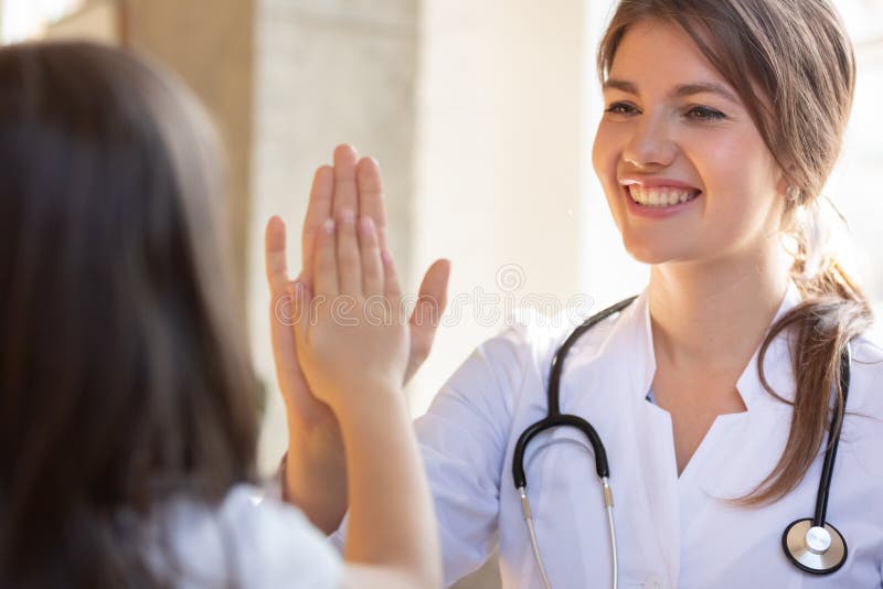 Smiling friendly pediatrician doctor giving five to little girl patient