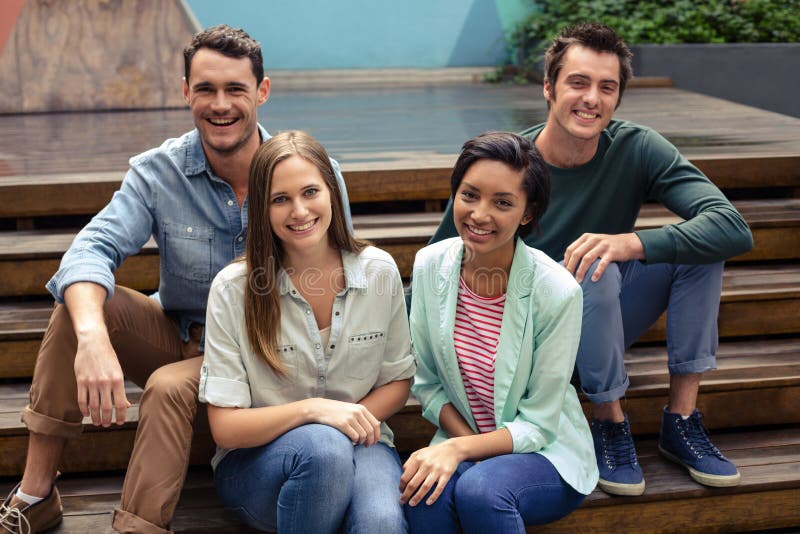 Smiling friends sitting on stairs stock images