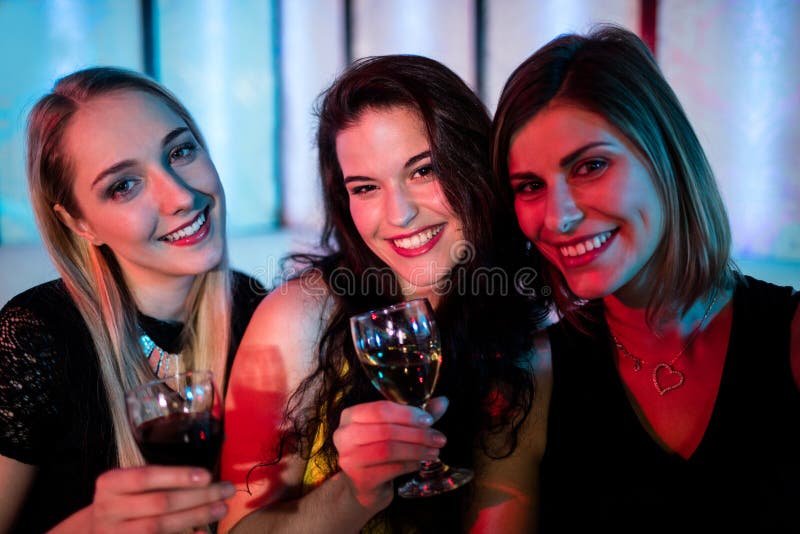 Smiling friends sitting together and having wine stock photo