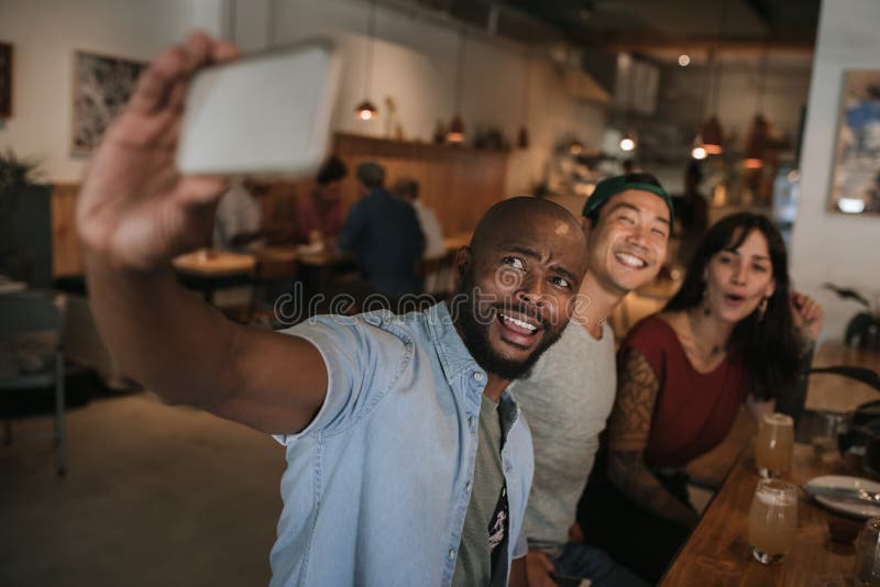 Smiling friends taking selfies together in a bar stock images