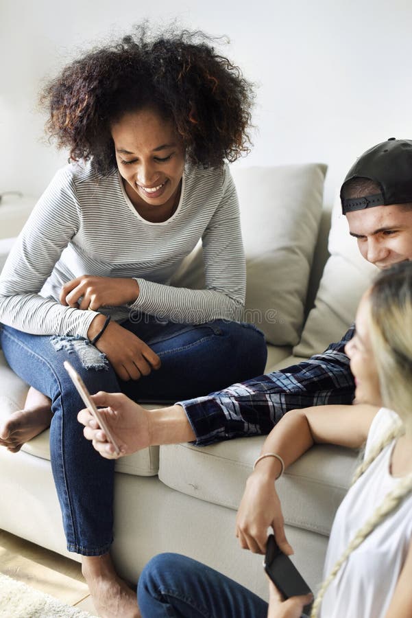 Smiling friends using smartphone together at home