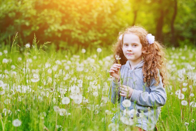 Smiling Girl Holding White Dandelion in Meadow. Stock Photo - Image of ...
