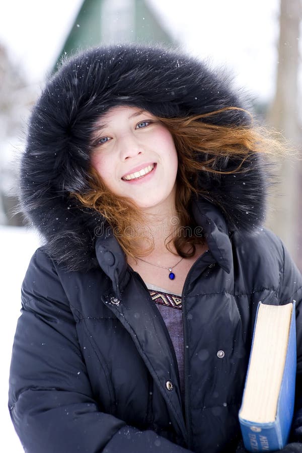 Smiling girl in the hood with blue book