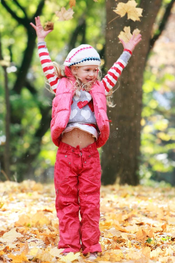 Smiling girl playing in autumn park