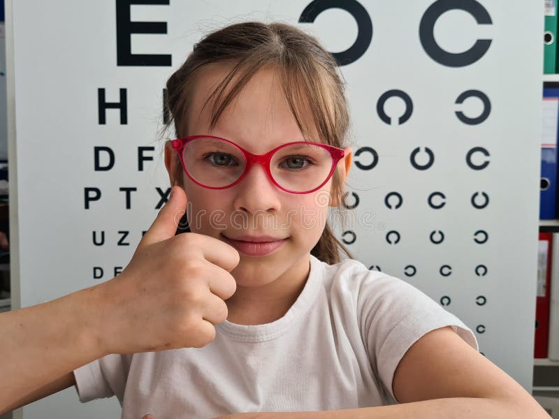 Smiling Girl Puts On Glasses With Blurred Eye Chart And Holds Thumbs Up Stock Image Image Of