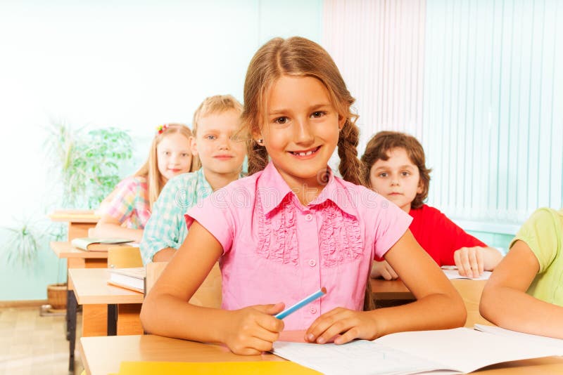 Smiling girl sitting at desk in classroom stock image