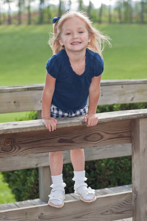 Smiling girl standing on the fence royalty free stock photos