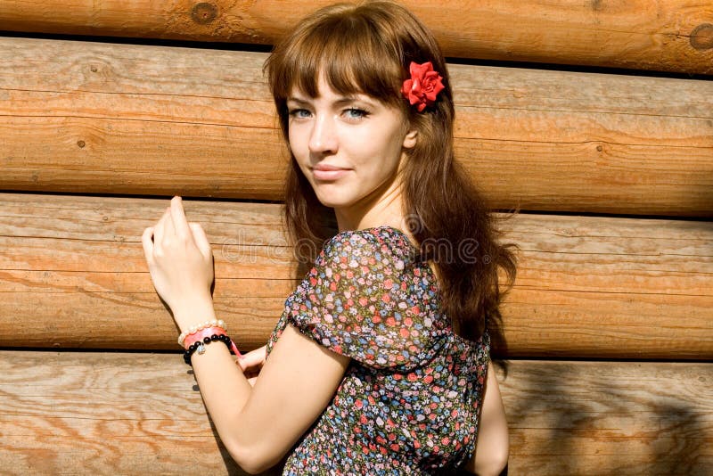 Smiling girl standing near wooden house