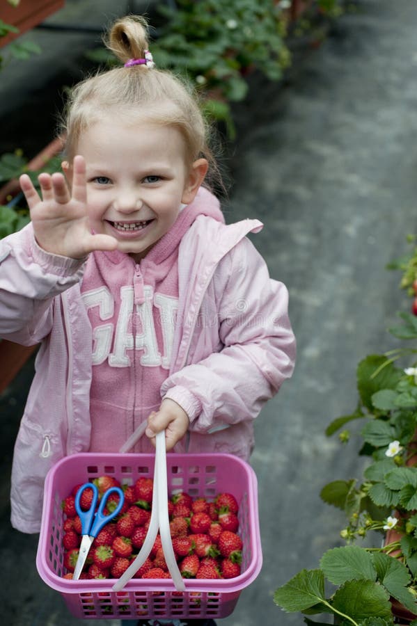 Smiling girl with strawberry basket in the field