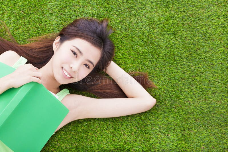 Smiling girl student laying down on a meadow