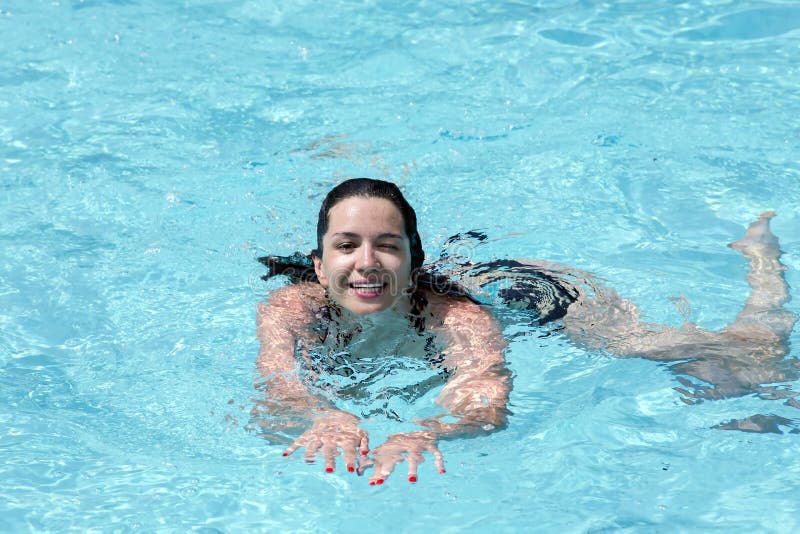 Smiling girl training in a turquoise water outdoor swimming pool