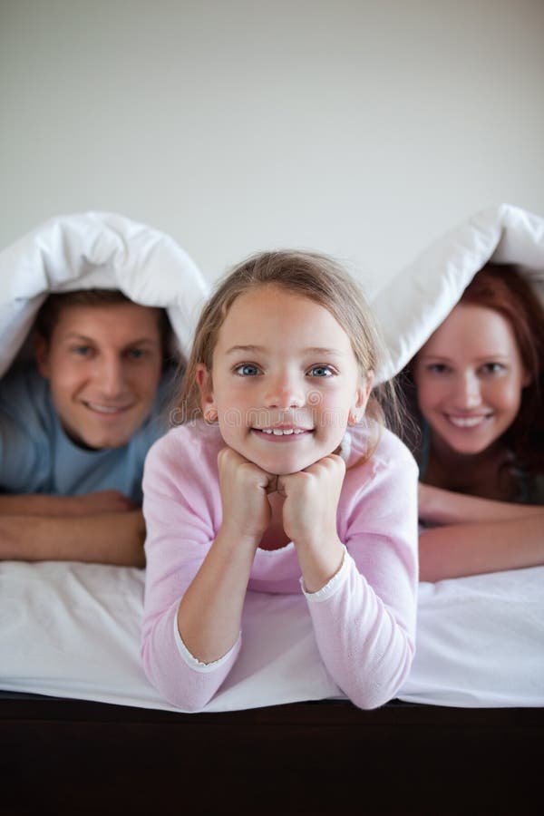 Smiling Girl Under Bed Cover with Her Parents Stock Photo Image of