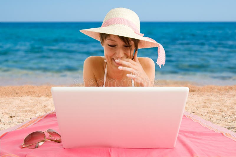 Smiling girl using laptop at the sea