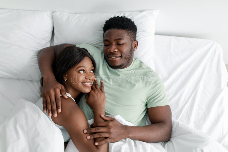 Smiling Glad Millennial African American Guy Hugging And Looking At Female Lies On White