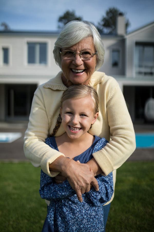 Smiling grandmother and granddaughter embracing each other in garden. 