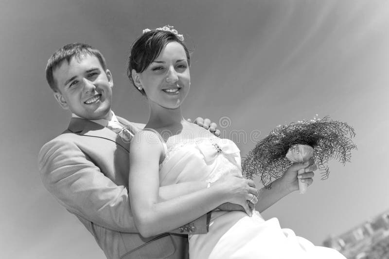 Smiling groom and bride against sky