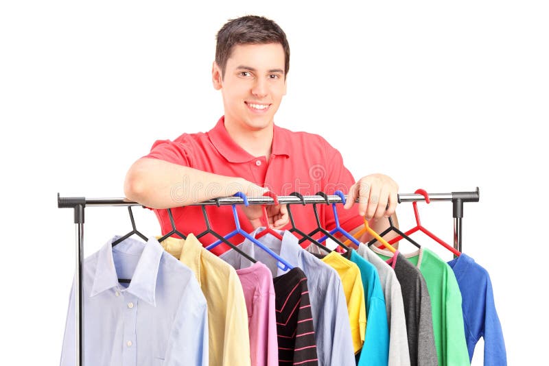 A smiling guy posing on a hang rail full of clothes royalty free stock photo