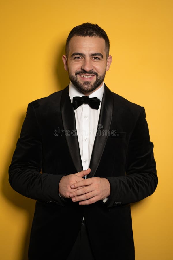 Smiling handsome man in black tuxedo with hands folded looking on camera, work profession lifestyle. Handsome young