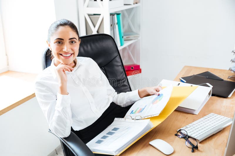 Smiling happy businesswoman holding reports and looking at camera