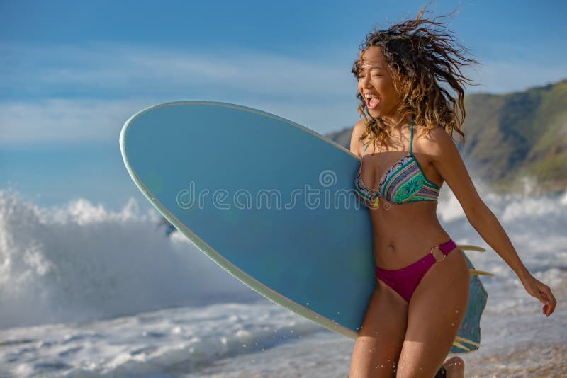 Smiling happy girl on a beach with surfboard