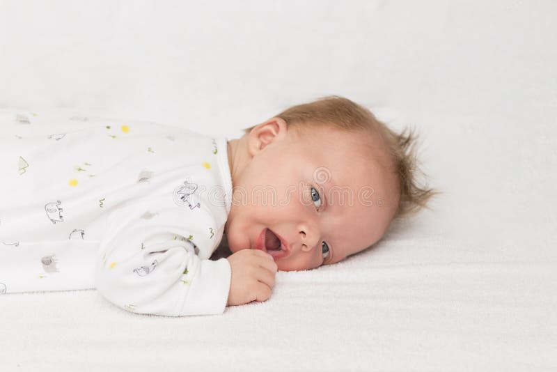 Beautiful And Sweet Newborn Baby Lying Face Down On The Bed Raising His