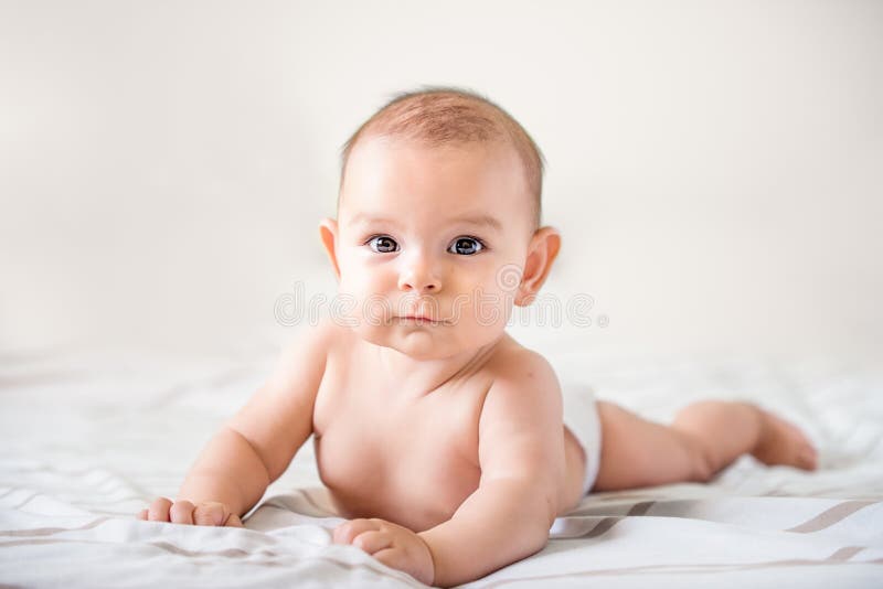 Smiling happy newborn infant baby tummy time on bed bright airy copy space childhood