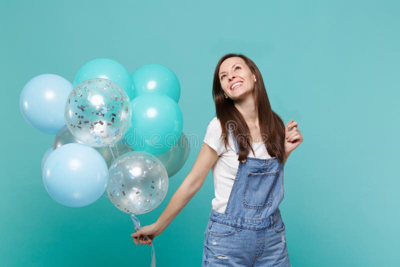 Smiling happy pensive young woman in denim clothes looking up celebrating and holding colorful air balloons isolated on stock images Smiling happy pensive young woman in denim clothes looking up celebrating and holding colorful air balloons isolated on stock images