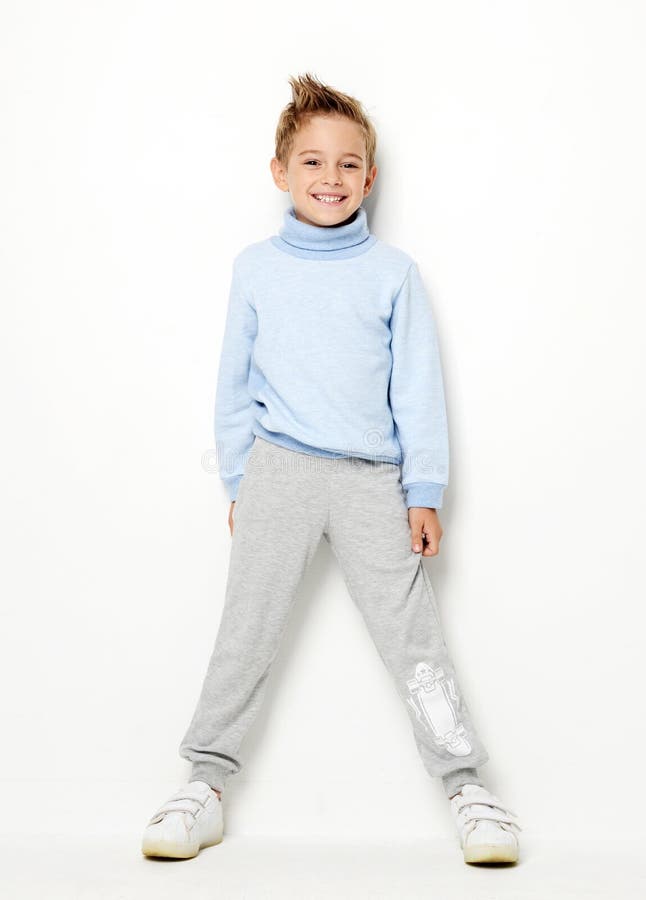 Smiling happy young boy standing laughing in light blue sweater royalty free stock image Smiling happy young boy standing laughing in light blue sweater royalty free stock image