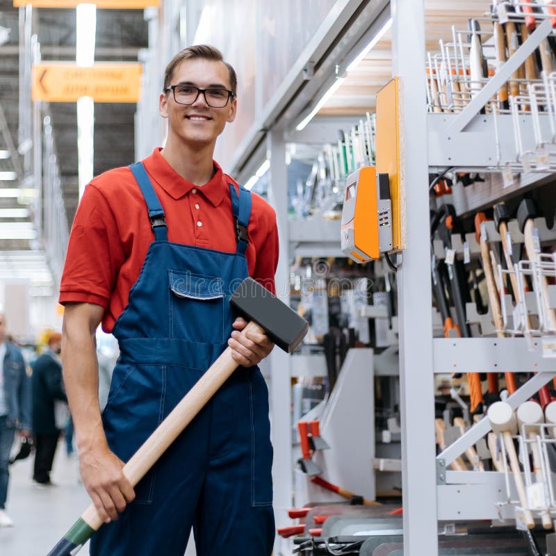 Smiling Hardware Store Clerk with a Large Sledgehammer Standing in the