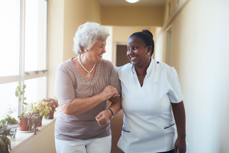 Smiling home caregiver and senior woman walking together