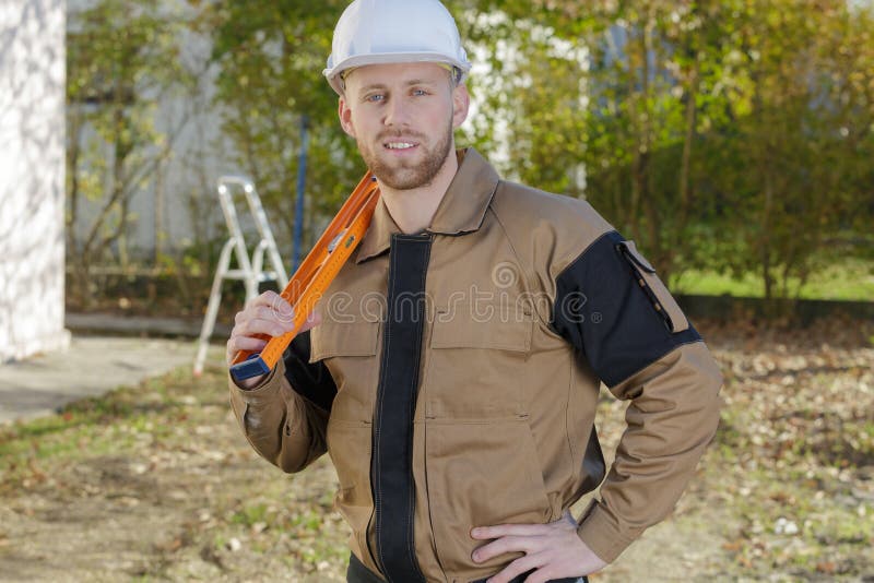 Smiling home inspector holding level at construction site.