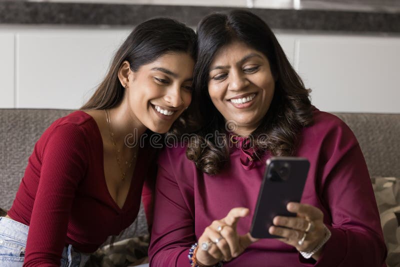 Smiling Indian woman and daughter using smartphone royalty free stock image