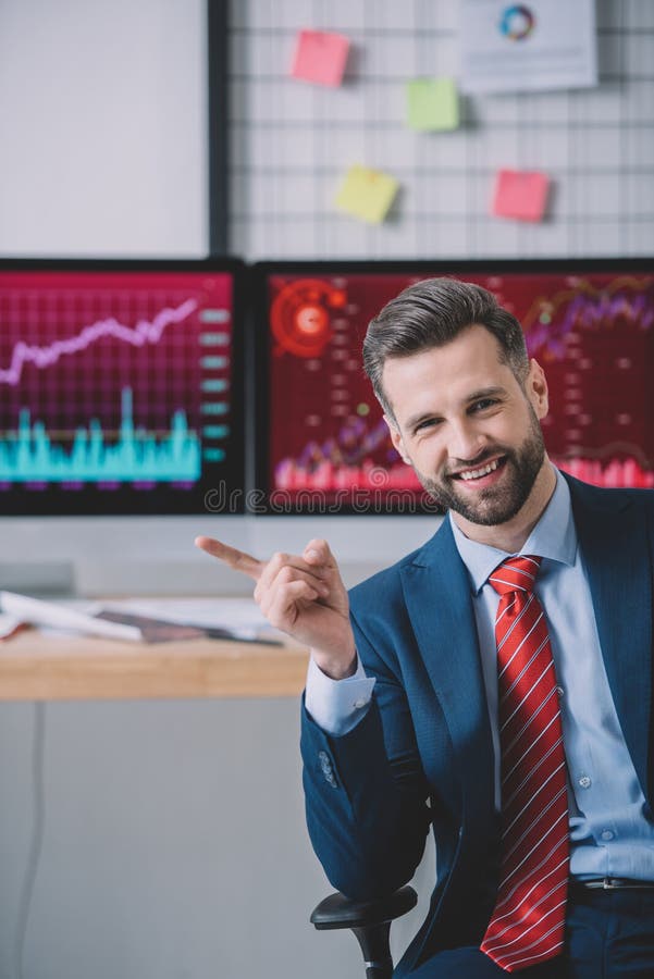 Smiling information security analyst pointing with finger near computers on table stock photography