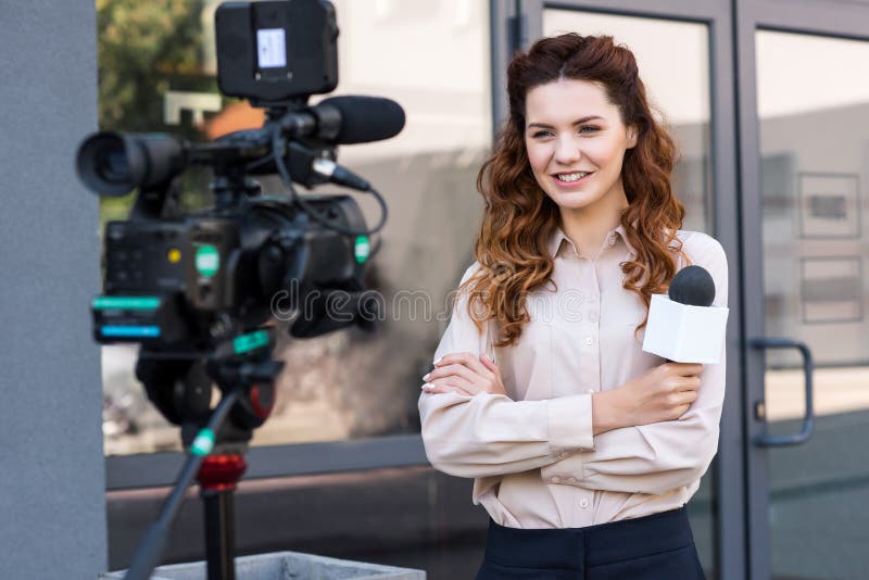 Smiling Journalist with Microphone Standing in Front of Digital Stock