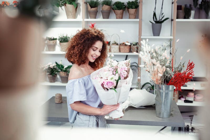 Smiling joyful red-haired florist enjoying appearance of freshly-made bouquet stock photography