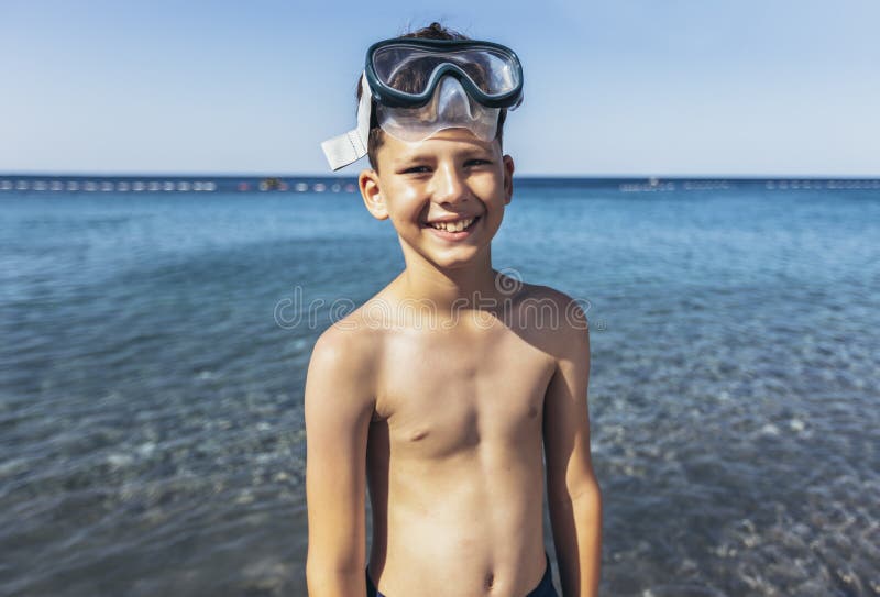 Smiling little boy with scuba mask by the sea