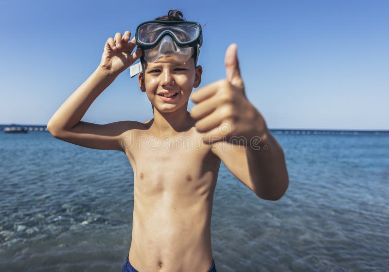 Smiling little boy with scuba mask by the sea